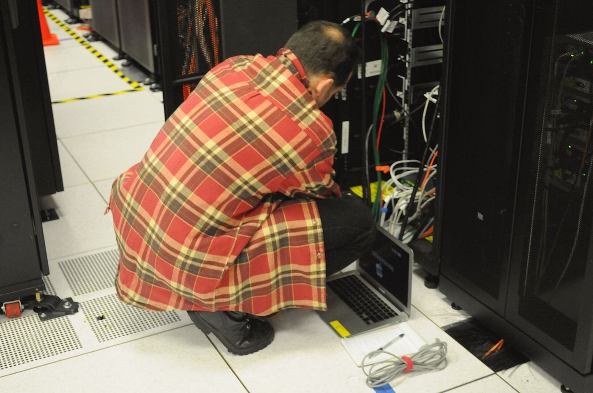 Techniker mit Notebook arbeitet an einem Serverschrank